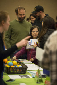 People talking to a person at a vendor table at the wellness conference