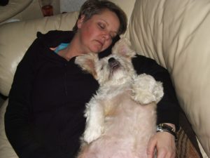 Person napping with their dog on a couch