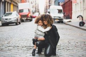 curly haired mother and daughter posing on a cobble stone street
