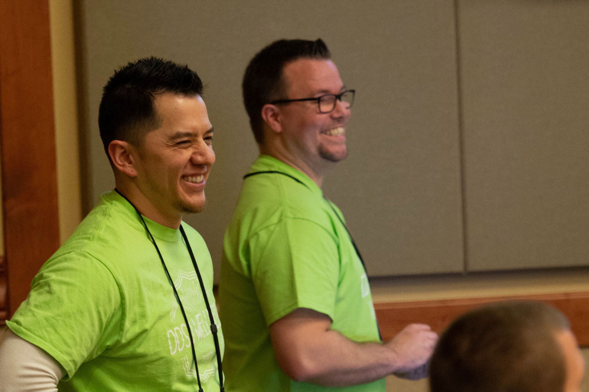 two people in green shirts laughing
