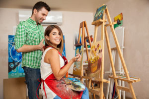 Person smiles while participating in a paint lesson