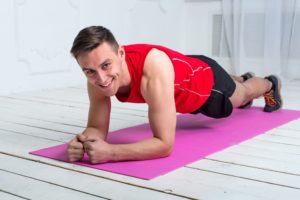 Person does a plank exercise on a pink yoga mat