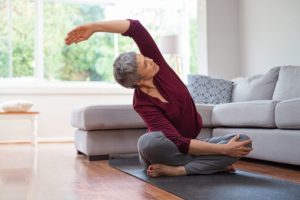 Person stretches on a yoga mat in a living room