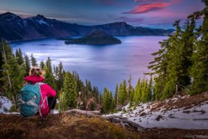 Person sits looking at Crater Lake, Oregon, during sunset