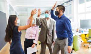 Group of employees high fives while wearing face masks