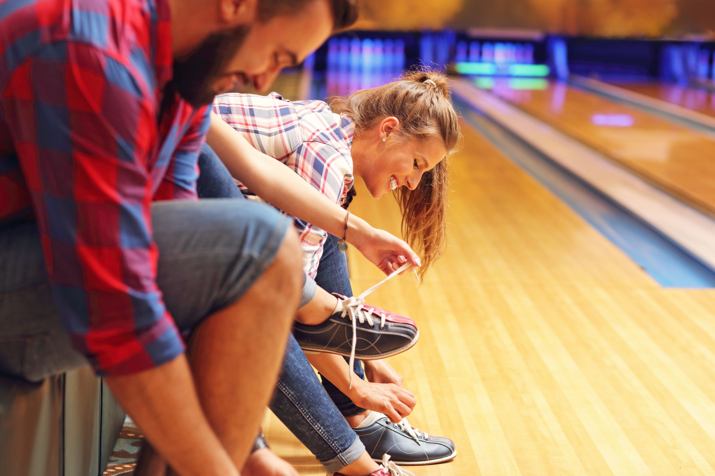Two people smile while putting on bowling shoes before bowling