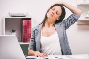 Person sits at their desk doing neck stretches