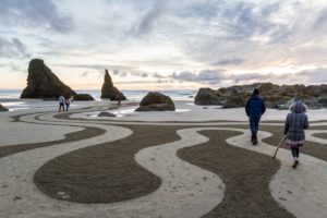 People walk through the sand labyrinth on the Bandon beach