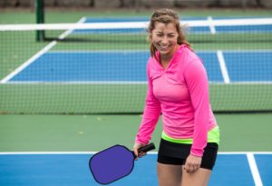 Person smiles as she gets ready to play pickleball