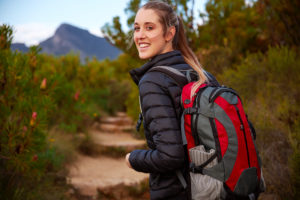 A person smiles while hiking on a trail