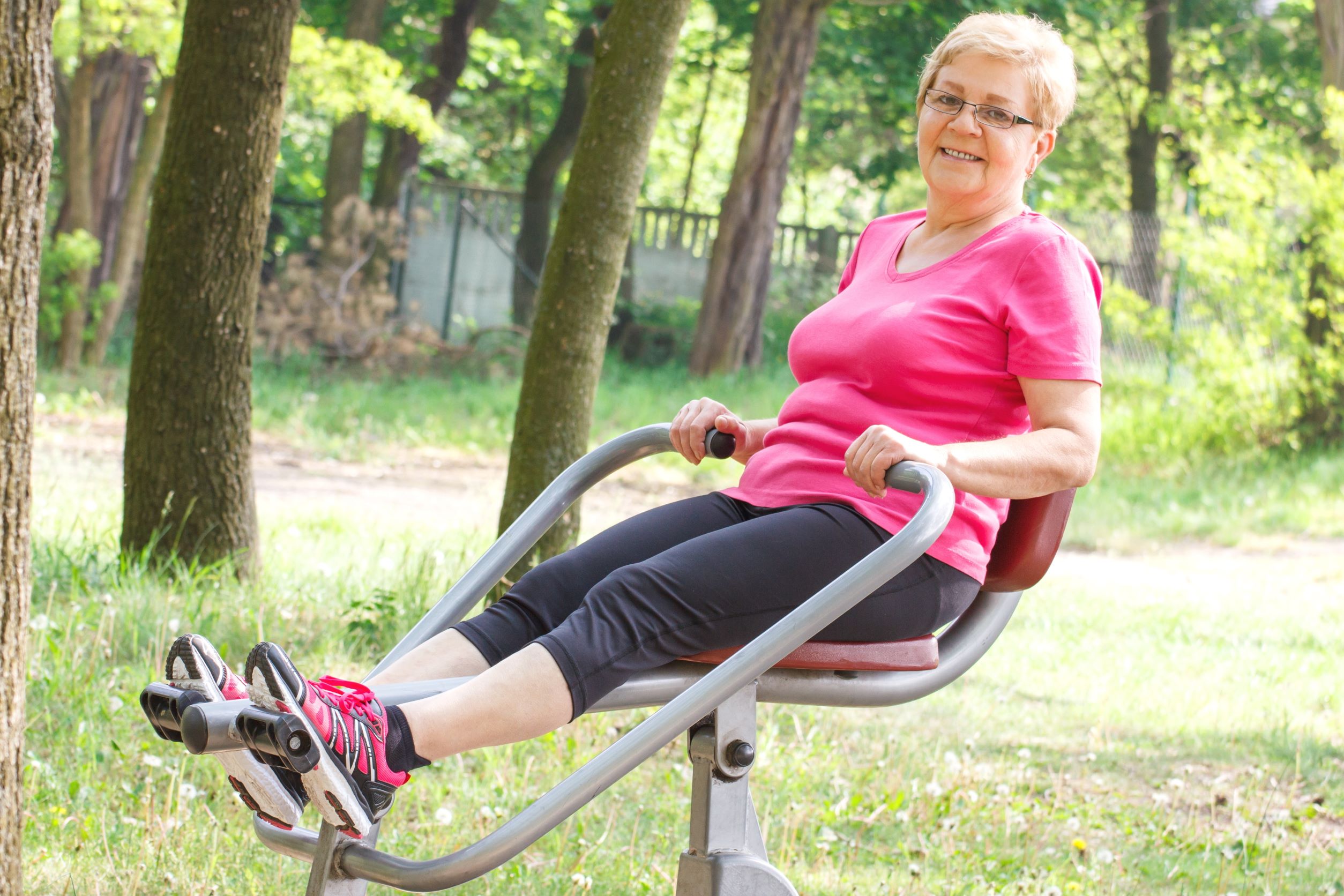 Person takes a break while using outdoor exercise equipment